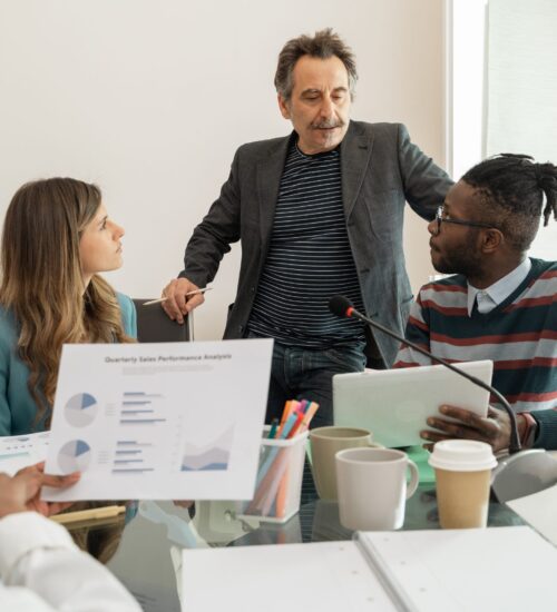 Diverse Team Analyzing Business Performance Multicultural team engaged in business analytics discussion - lively collaboration in a modern office setup - showcasing teamwork and strategy planning.